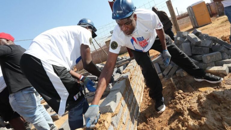 Dikembe Mutombo (right) uses a trowel to put cement on a low wall while taking part in construction work as part of a Basketball Without Borders Africa program in a township in Johannesburg in August 2018.