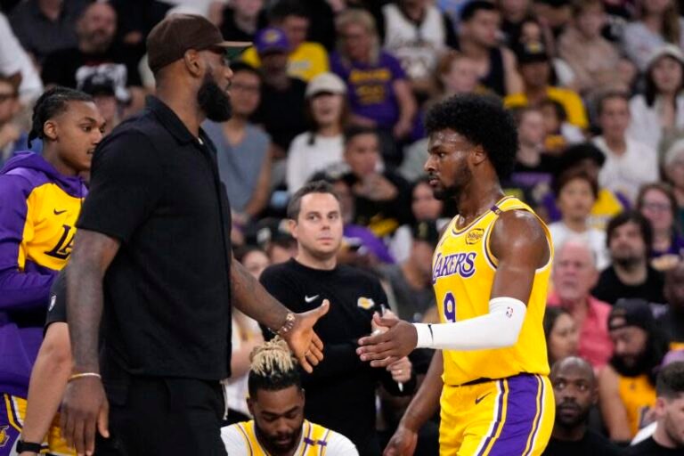 Los Angeles Lakers' LeBron James, left, greets his son, Bronny James, as Bronny walks off the court during the first half of a preseason NBA basketball game, Friday, Oct. 4, 2024, in Palm Desert, California. (AP Photo/ Mark J. Terrill)