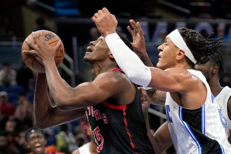 Toronto Raptors' Christian Koloko, left, looks to shoot past Orlando Magic's Paolo Banchero during the first half of an NBA basketball game Friday, Dec. 9, 2022, in Orlando, Florida (AP Photo/John Raoux)