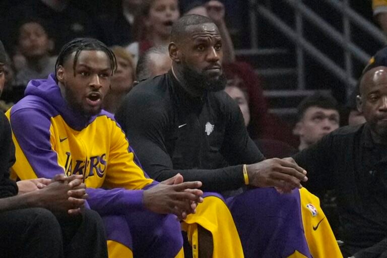 LeBron and Bronny James sit on the Lakers bench and react to action during a lopsided loss to the Cavaliers.