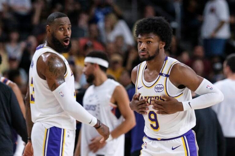 Laker guard Bronny James steps onto the court as his father and teammate LeBron James greet him in a preseason game.